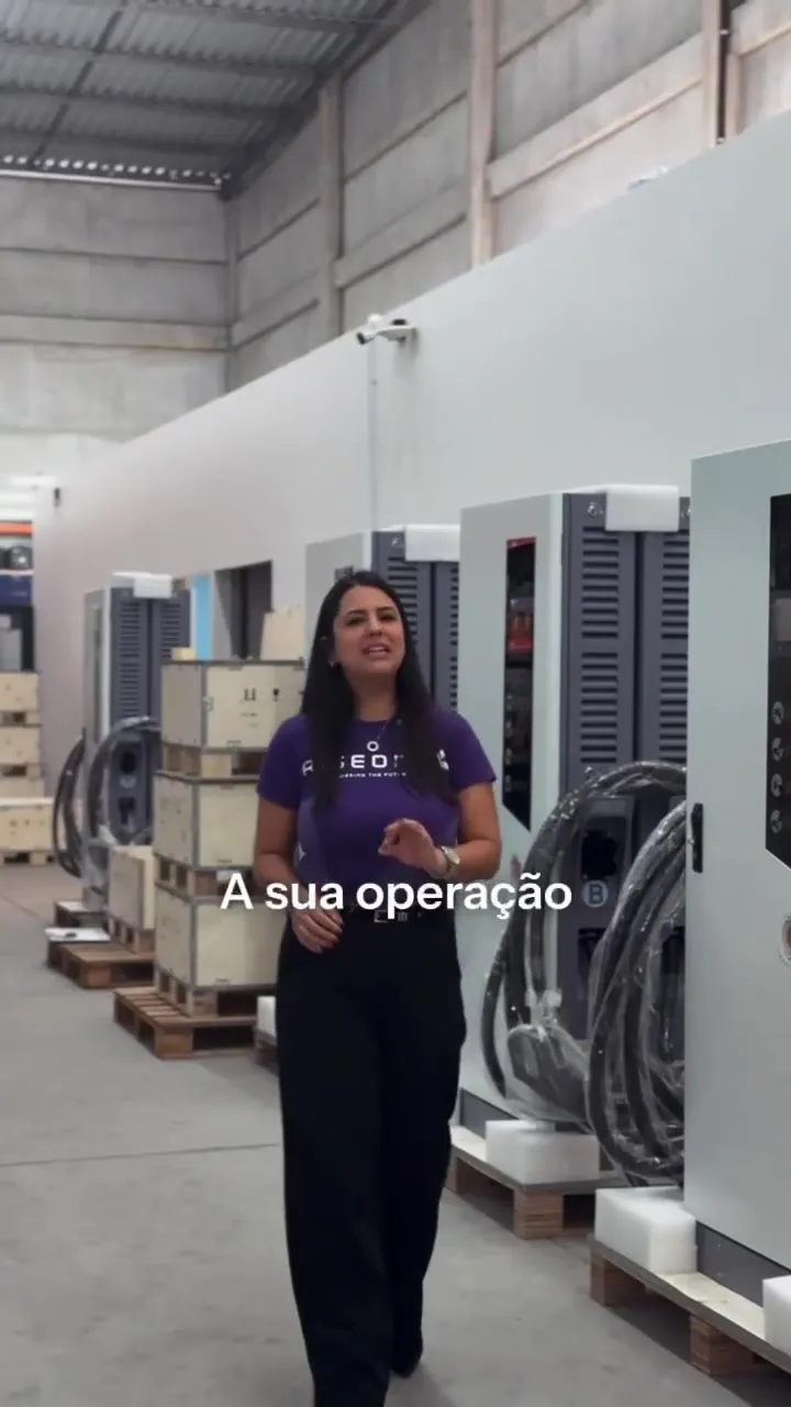 Apresentadora da Riseon no galpão, entre carregadores UltraFast embalados em paletes